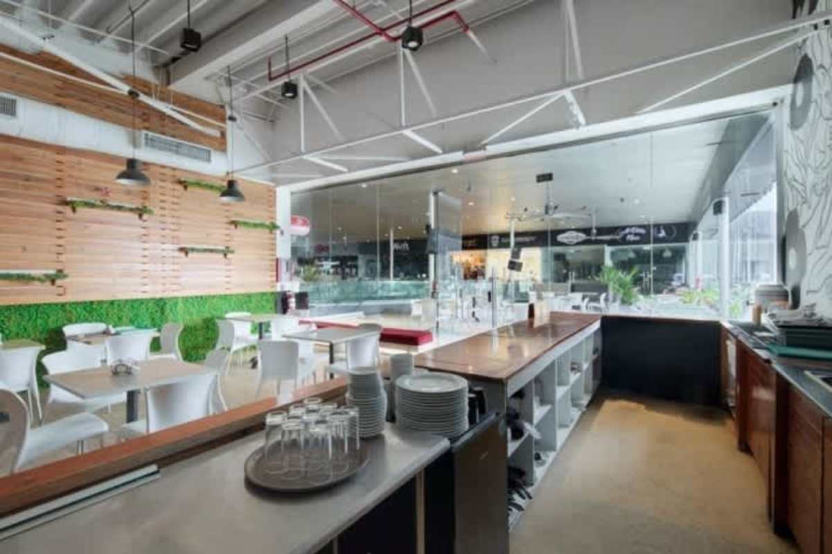 Contemporary restaurant with open ceiling, wood panel walls, greenery accents and dining area at Balboa Boutique