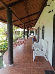 Covered porch with tiled floor, black columns, hammocks and garden view in Las Lajas Chame Panama
