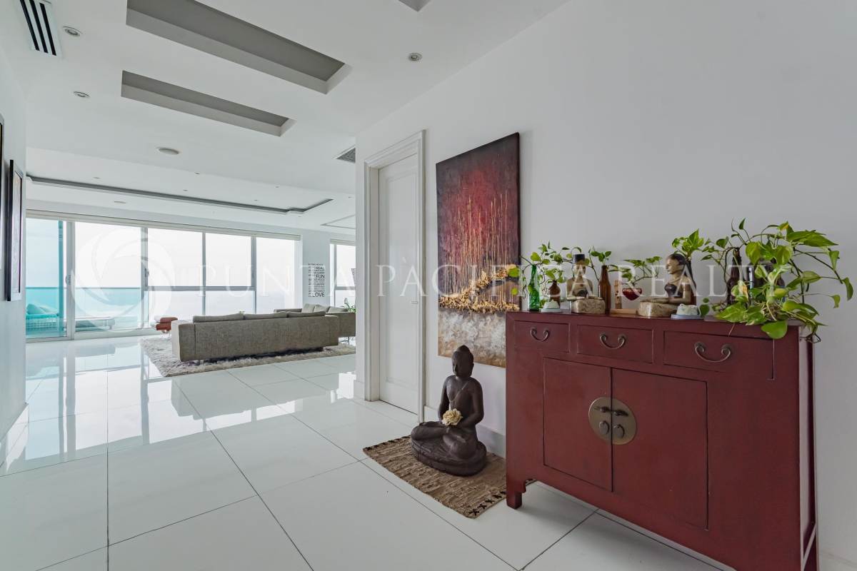 Modern open living and dining room with floor-to-ceiling windows overlooking Pacific Ocean at Ocean One Costa del Este