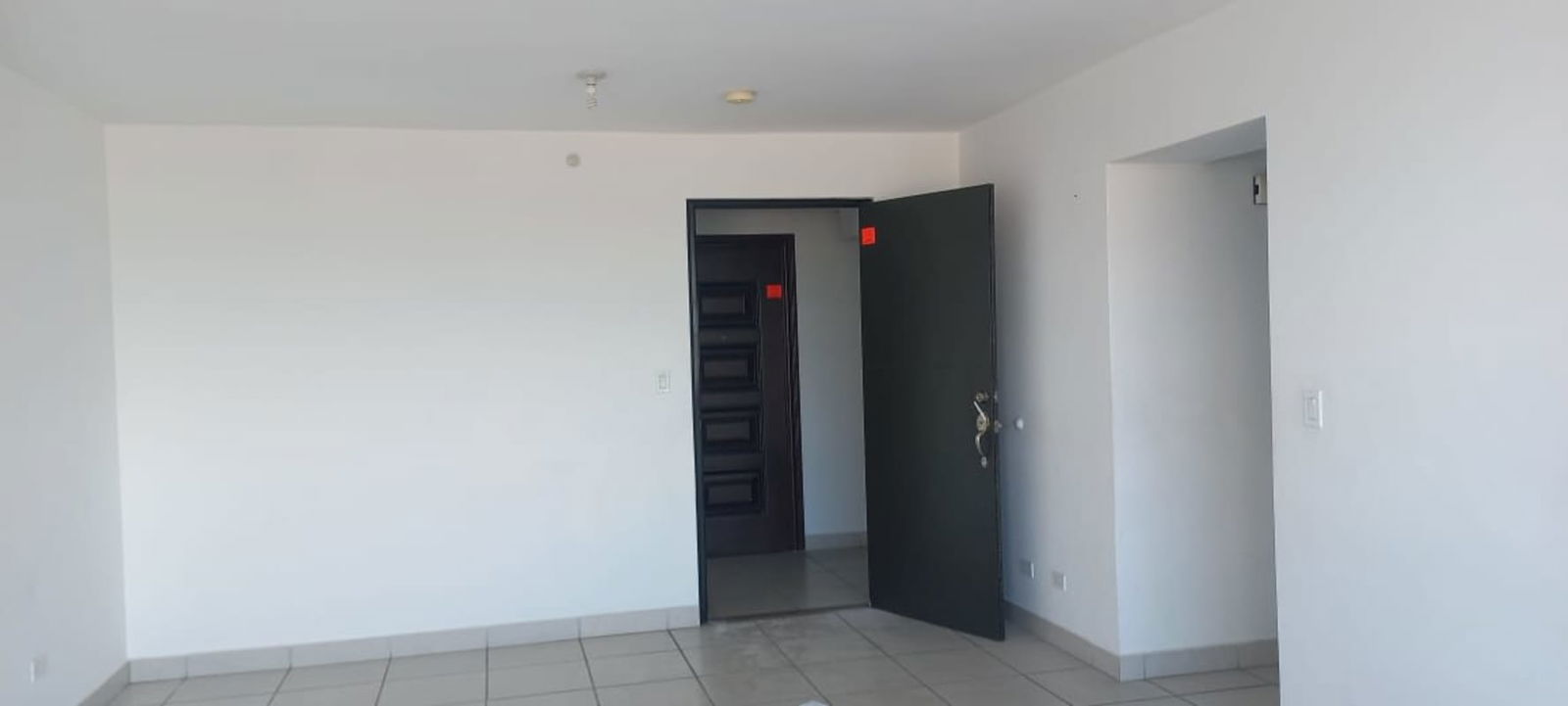 Empty entrance and living room with tiled floor and black door in PH Lefevre 75 Panama