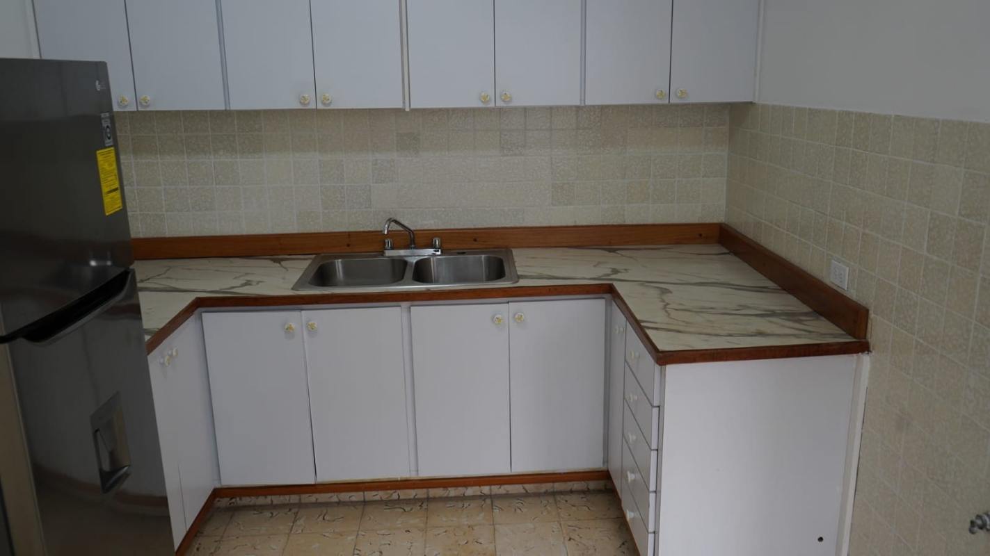 Traditional kitchen with double stainless sink marble-pattern countertop and white cabinets in PH Trébol