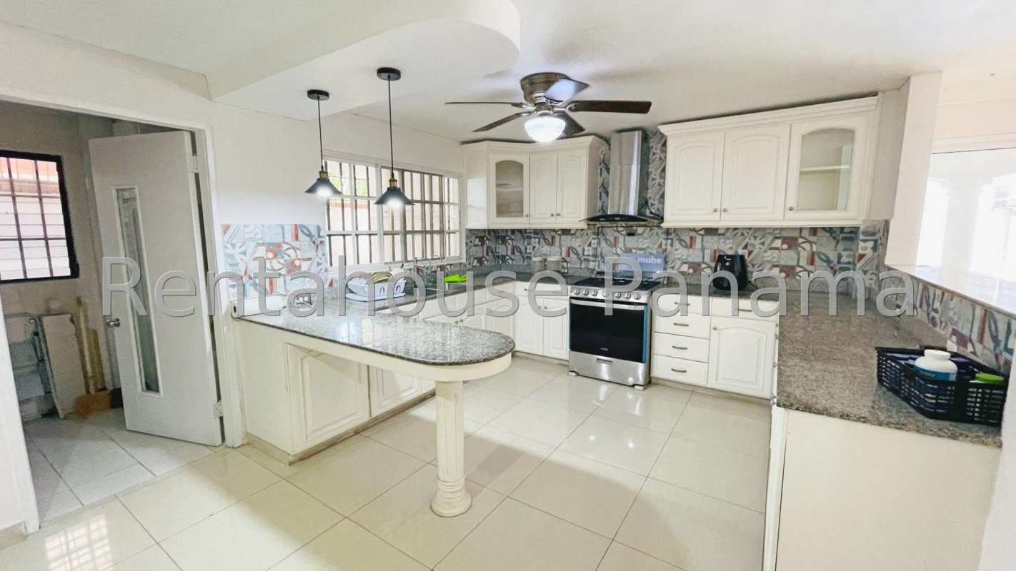 Bright kitchen with granite countertops, island, pendant lamps and breakfast bar in La Alameda house Panama