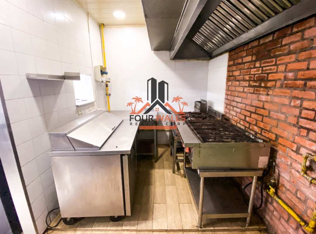 Fully equipped restaurant kitchen with brick accent, stainless appliances, and ventilation hood in Balboa Boutiques Panama City