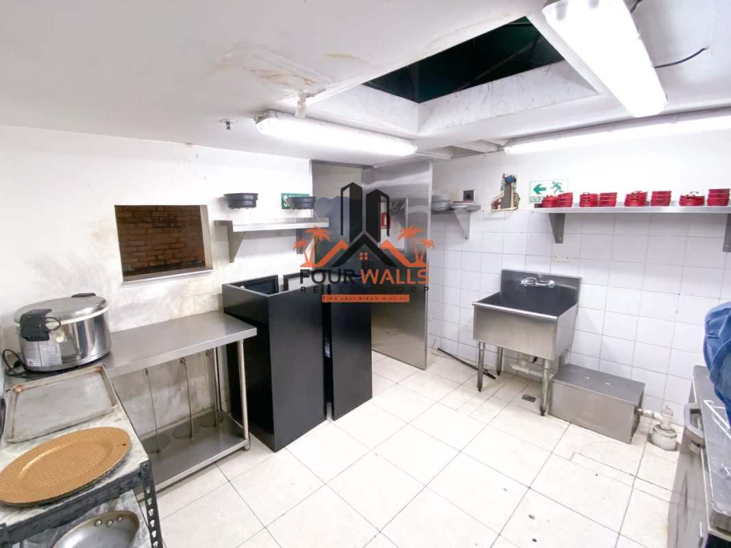 Industrial commercial kitchen with stainless appliances and white tile walls in Balboa Boutiques Avenida Balboa Panama