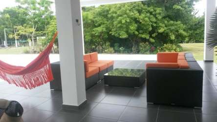 Covered terrace with hammock, orange seating, garden view at luxury home Santa Clara Panama