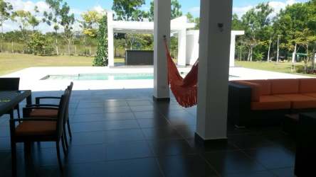 Bright dining room with dark wood table, white chairs, large windows natural light at Santa Clara luxury estate Panama