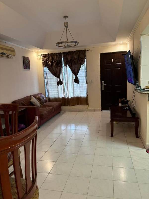 Living room with tiled floors, brown sofa set, dining table, vaulted ceiling in Brisas del Golf house Panama