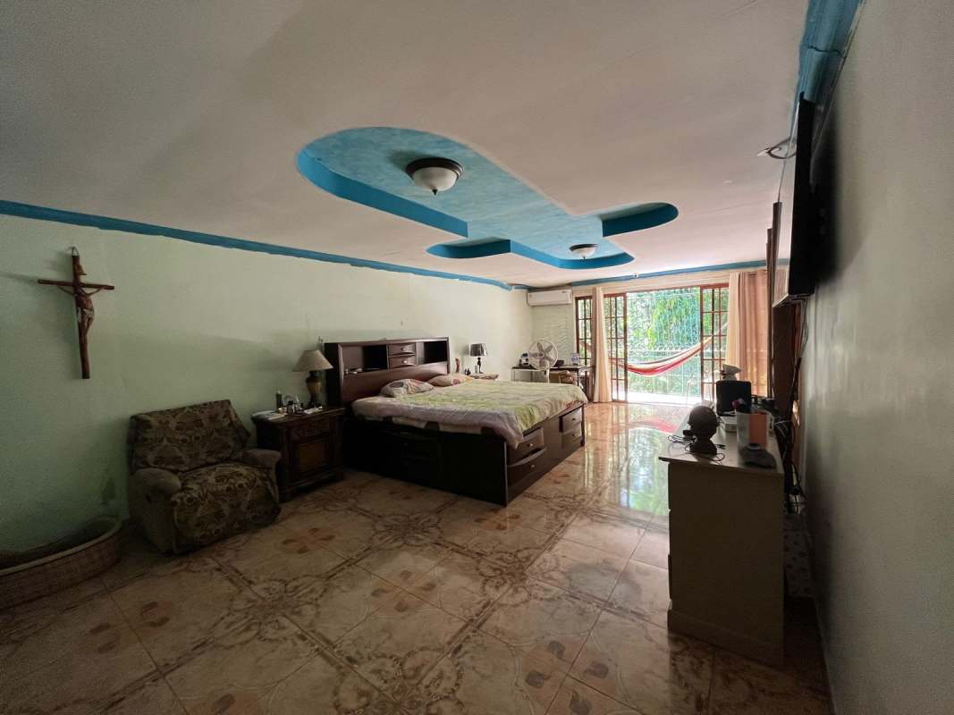 Bright living room with orange wall, striped sofas, glass table Villa de Las Fuentes Panama