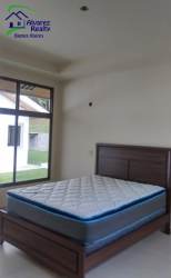 Minimalist bedroom with large window, wooden bed frame, ample light in Las Villas Volcán