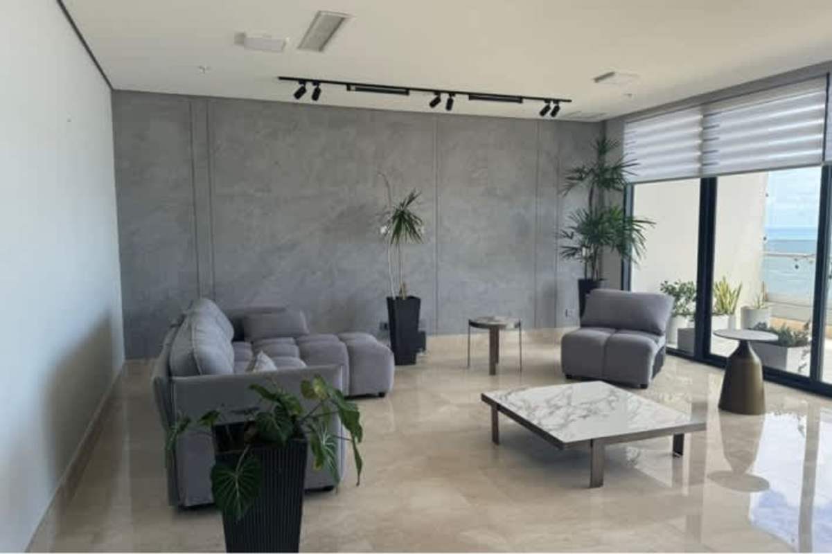 Modern living room with floor-to-ceiling windows, gray sectional sofa, marble floor, ocean view at PH Mirador Costa del Este Panama