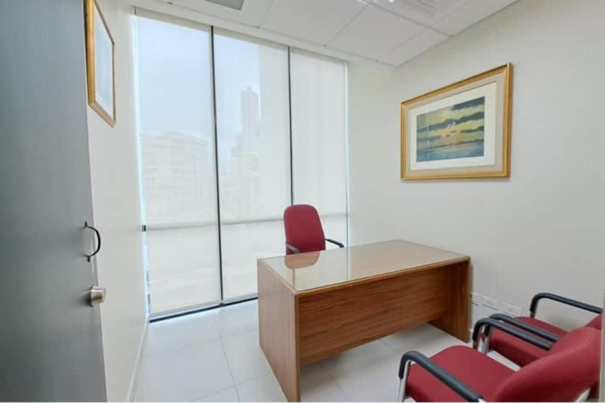 Small conference room with round table, red chairs, flat-screen TV in Marbella office at PH Banco General Tower Panama City