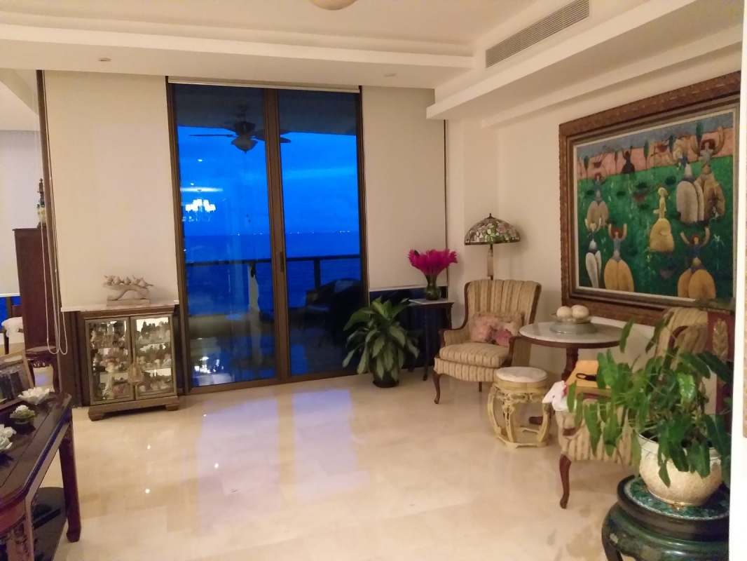 Traditional living space with striped chairs, marble floors, balcony with ocean view in PH Regalia Costa del Este Panama