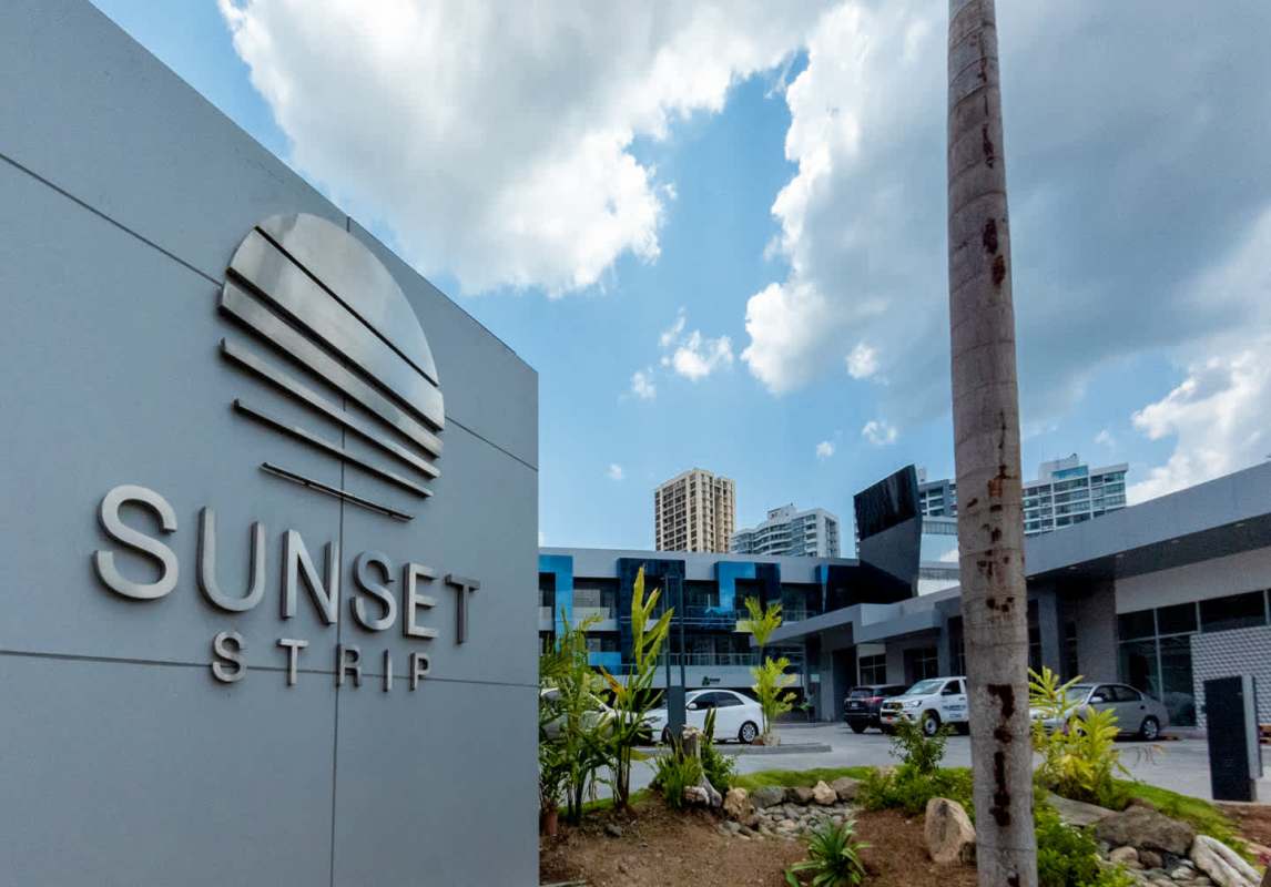 Modern commercial plaza with Sunset Strip signage and mid-rise building in busy Panama City