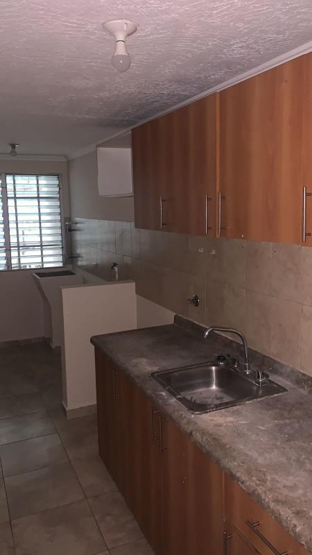 Kitchen with wood finish cabinetry, tile backsplash and window with security bars at PH Parque Lefevre Panama City