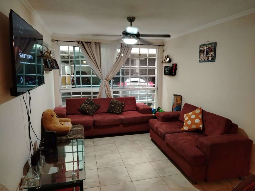 Contemporary living room with maroon sectional sofa, large window, ceiling fan at PH Parque Lefevre Panama City