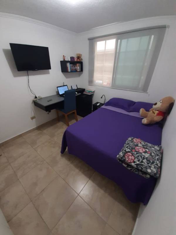 Compact bedroom includes desk, wall-mounted TV, bookshelf, window with blinds at PH Parque Lefevre Panama City