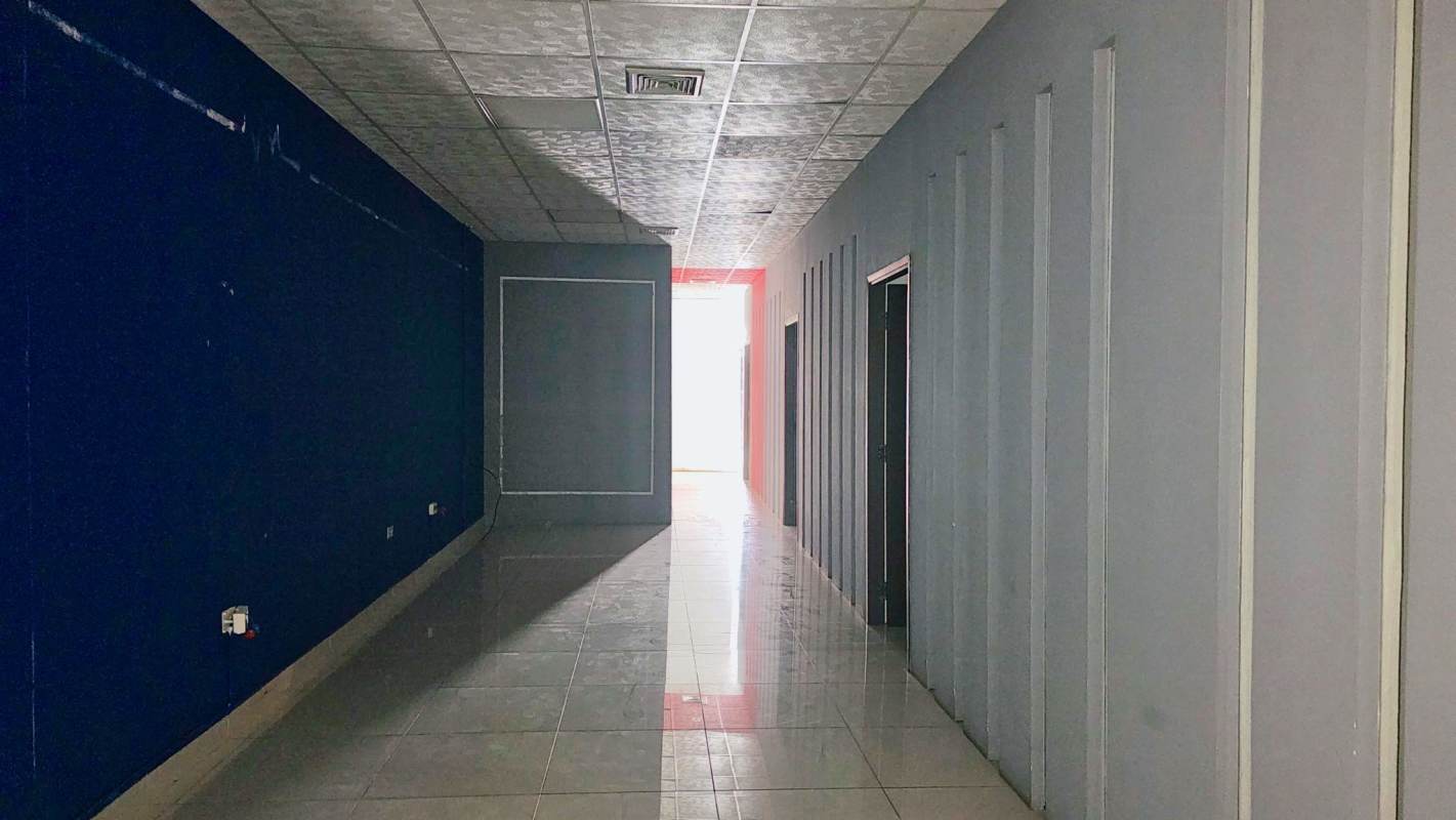 Interior corridor with blue walls, tiled floors, in commercial building Display Plaza Panama