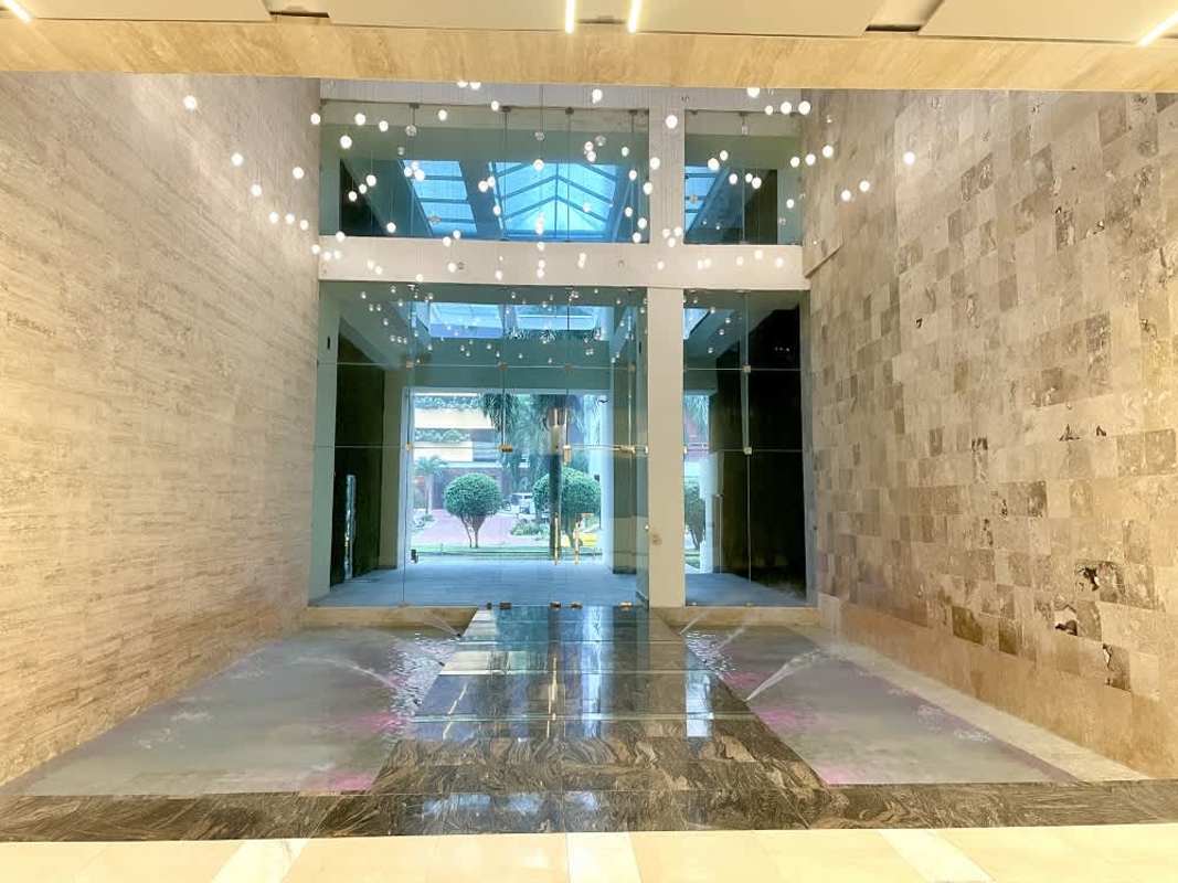 Building lobby with stone walls, hanging lights, water feature at PH Santa Maria Court Panama