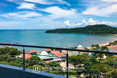 Bright open-concept living room with kitchen, island, modern furniture and large windows with ocean views