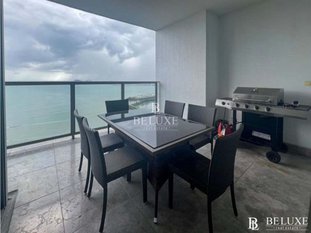 Balcony dining space with glass railing and ocean view at PH Yoo Panama