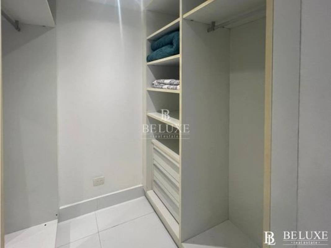 Walk-in closet with built-in shelves and drawers at PH Yoo apartment Panama City