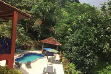 Rustic living room with stone wall, wood furniture, natural light, in Chame Panama mountain villa