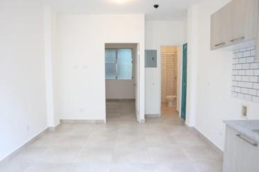 Minimalist kitchenette with subway tile backsplash and open hallway La Quince Santa Ana creative district Panama