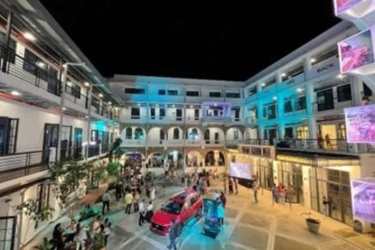 Illuminated multi-story building with courtyard retail and people at night La Quince Panama City
