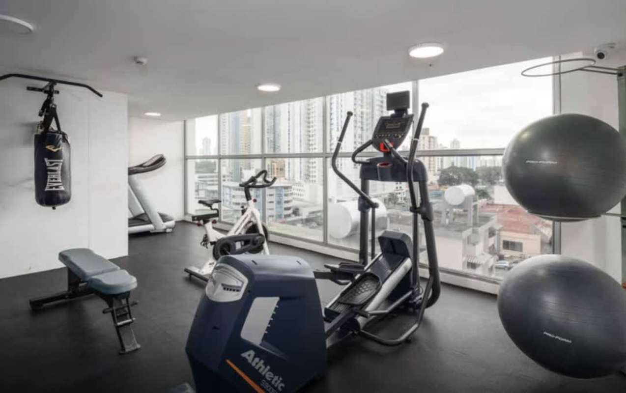 Modern gym with workout equipment and large windows in PH Gaudi Panama City
