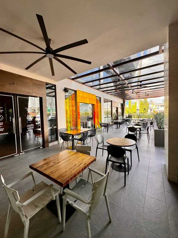 Covered outdoor patio with glass canopy, fan, and seating potential in Punta Pacífica commercial plaza