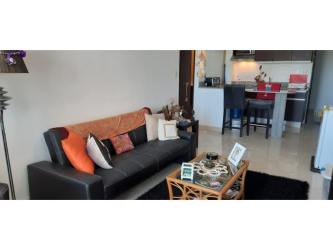 Modern living room with black sofa and open kitchen at PH Ibiza Playa Corona Panama beachfront apartment