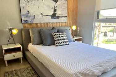 Two twin beds with minimalist decor and large window in guest bedroom Playa Caracol Panama