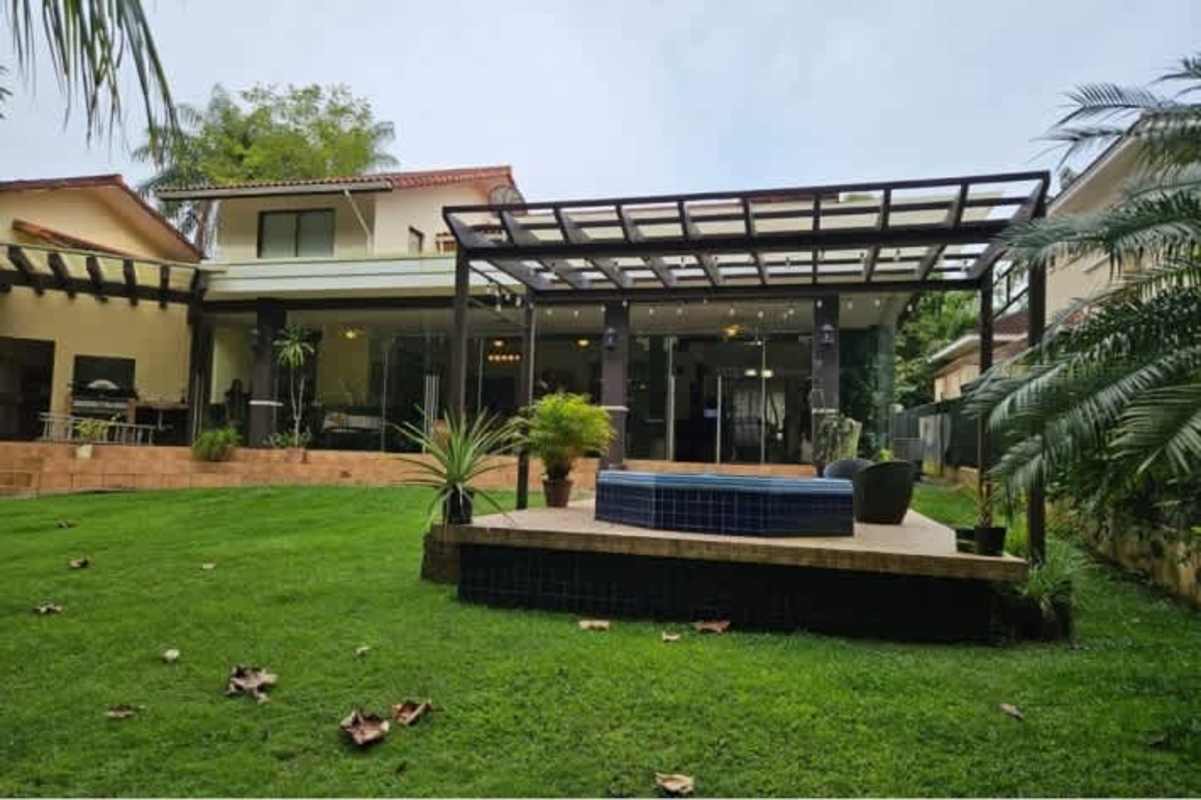 Luxury home's glass-enclosed terrace with lush garden and stone patio in Camino de Cruces Panama