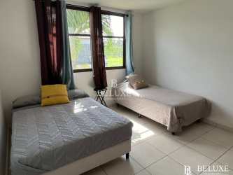 Living and dining open space in beach home with white sofa, glass coffee table, dining table and wall art in Piedras Gordas Village Panama