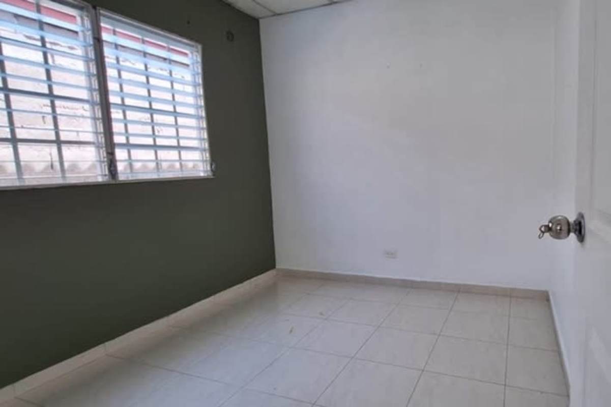 Bedroom with tiled floors, split AC, and barred window at Don Bosco house in Panama