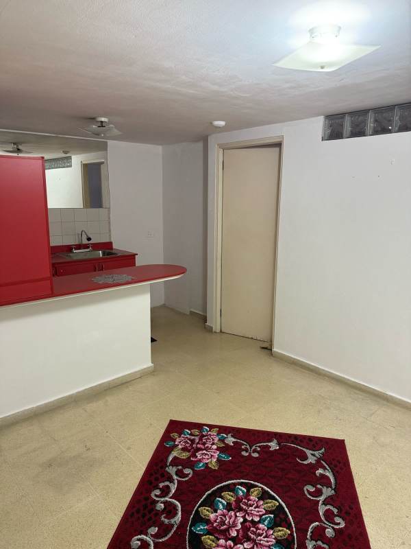 Compact kitchen with red counter, breakfast bar, and wall mirror in Beverly Plaza Rio Abajo Panama City