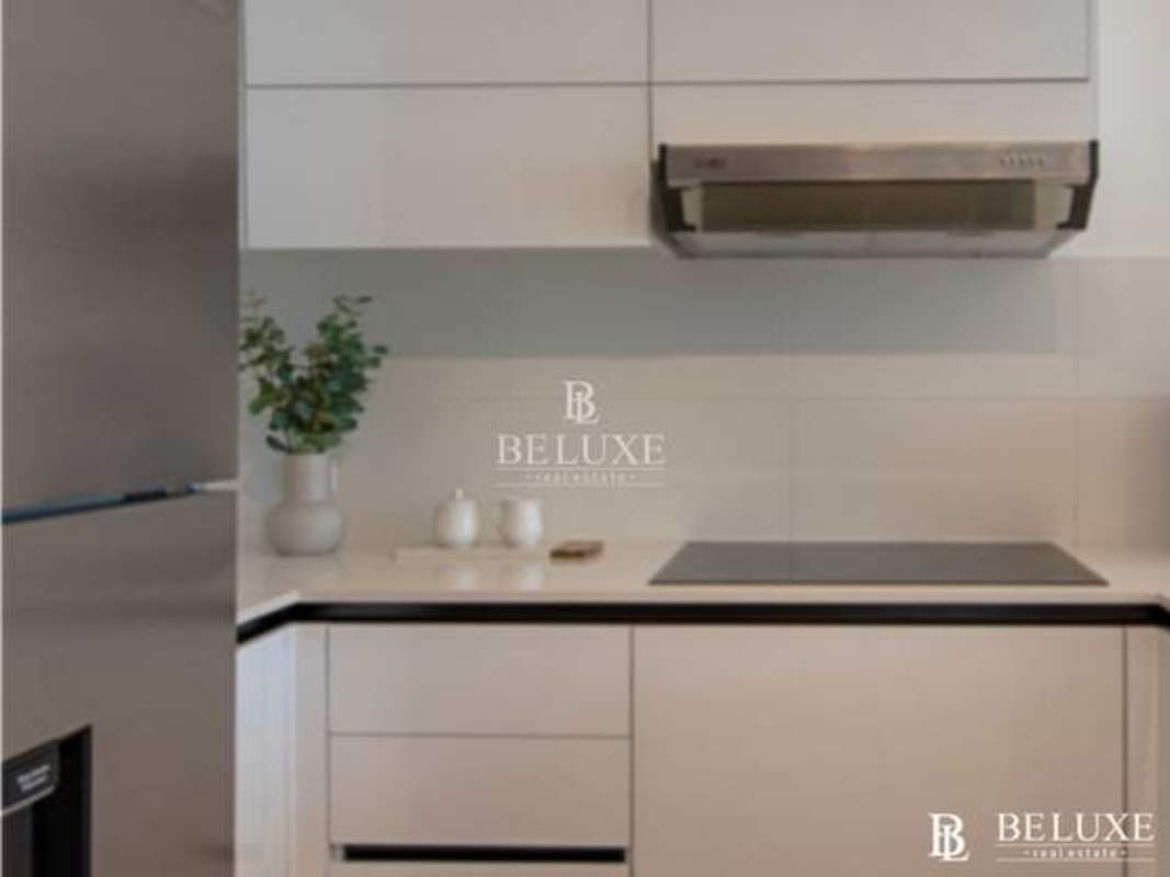 Sleek white kitchenette with built-in appliances and ceramic tile in smart studio PH Kyte Obarrio