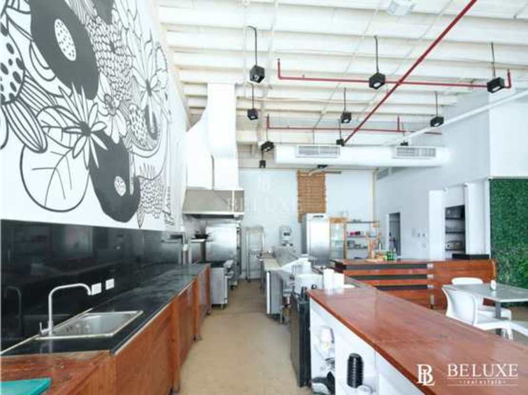 Industrial-style kitchen equipped with stainless steel appliances, open ceiling and bar counter in Plaza Comercial Balboa Panama