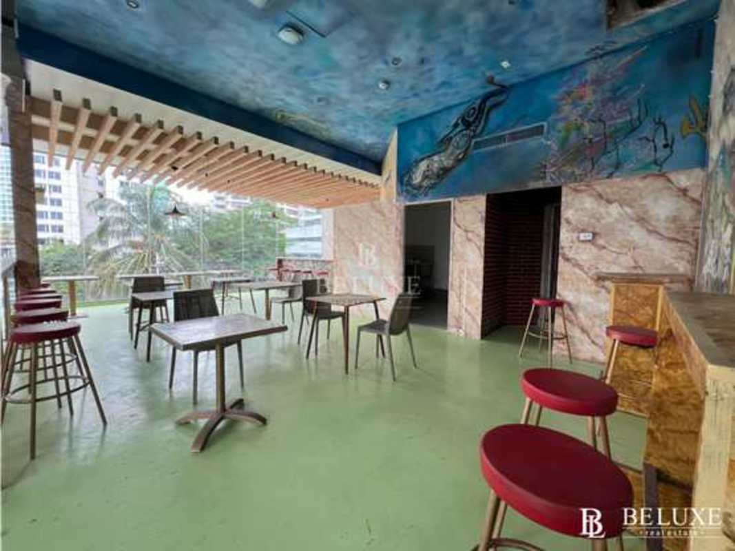 Indoor lounge bar with murals, glass wall view, eclectic furniture, Panama City