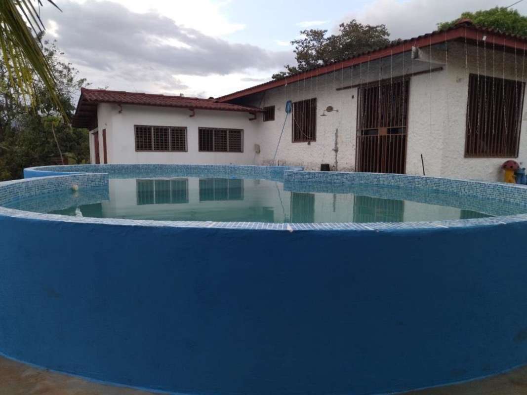 Blue above-ground pool in front of rustic white house near Pacora Panama