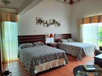 Guest bedroom with two double beds large windows balcony garden view Villas Decameron Panama