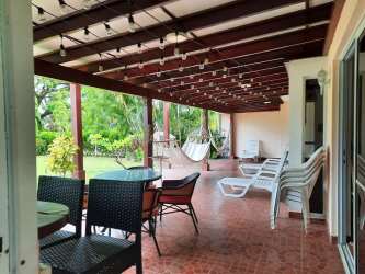 Tropical covered patio with hammocks rustic pergola overlooking lush backyard at Villas Decameron
