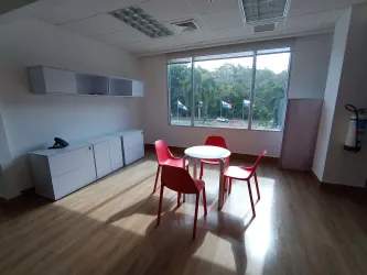 Office break area with round table, red chairs, wood floor near large window in Costa Verde Business Hub Panama