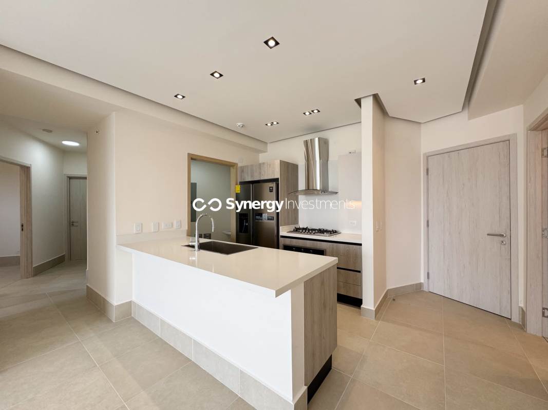 Open designer kitchen with island, stainless appliances, quartz countertops in luxury condo Santa María Panama