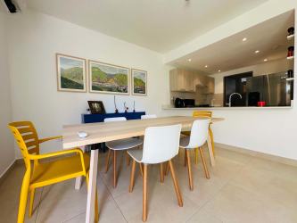 Dining room with open kitchen, wood table, tile floor in Panama Pacifico Howard house