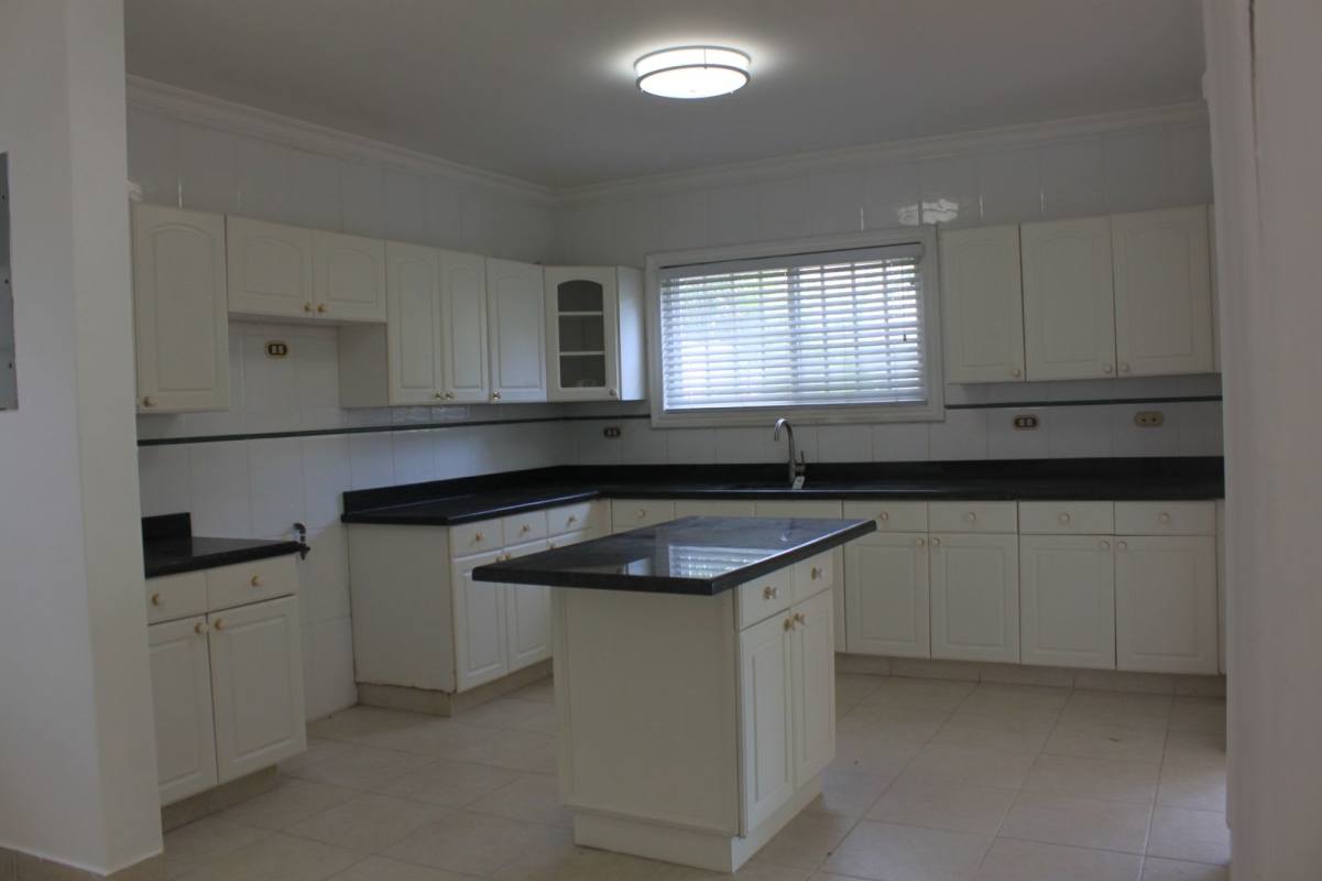 Bright kitchen with black granite, white cabinets, island and window in luxury rental Costa del Este