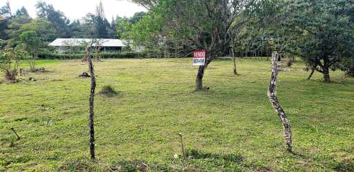 Open green lot with rustic fence posts, mountain backdrop, residential land in El Valle de Antón Panama