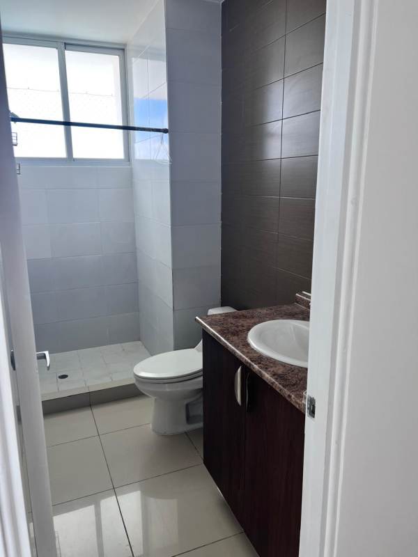 Dining area with glass table and turquoise chairs near bright window in Dos Mares apartment