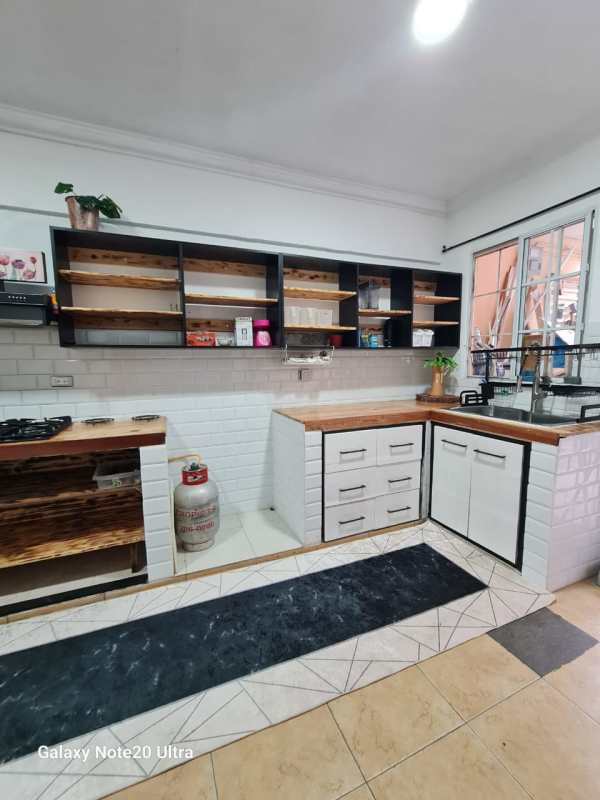 Shared rustic kitchen with wooden countertops, white tiles, open shelving La Loceria