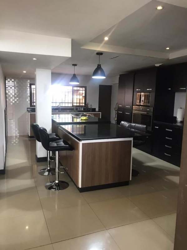 Green backyard garden with lawn, palm trees, basketball hoop and play space in El Dorado Panama home